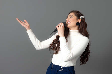 attractive female conference speaker during presentation, holds microphone and makes some gestures,...