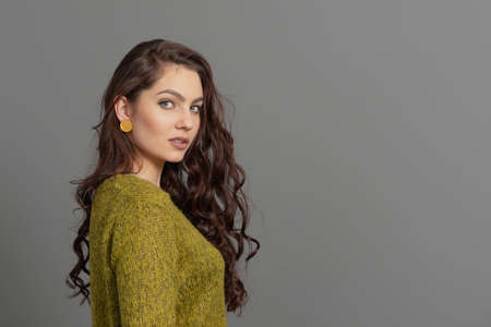 close-up portrait of beautiful sensual woman with long curly hair against gray backgroundの写真素材