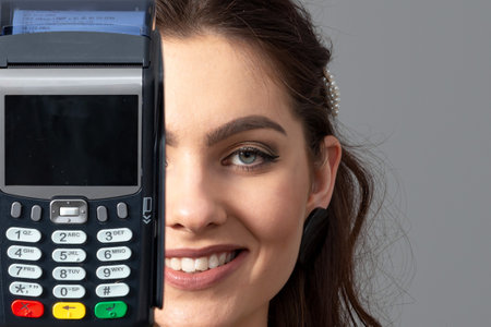 half a female face and a modern wireless bank card payment terminal, close-upの写真素材
