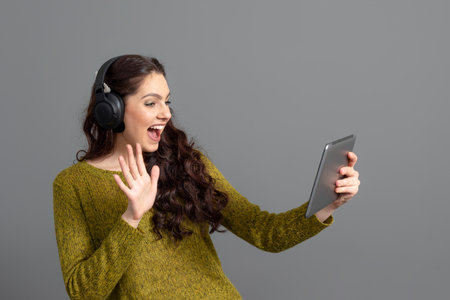 woman with headset and tablet in hand playing games and talking to friends online, modern entertainment conceptの写真素材