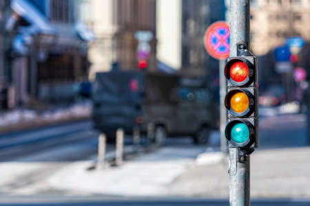 close-up of small traffic semaphore with red light against the backdrop of the city trafficの写真素材