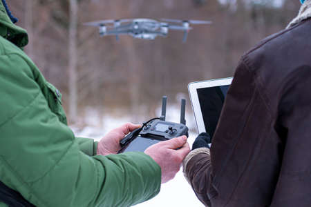 area planners survey the surroundings with a drone, close-up of a hand with a drone remote controller and a laptop, area planning and monitoring conceptの写真素材