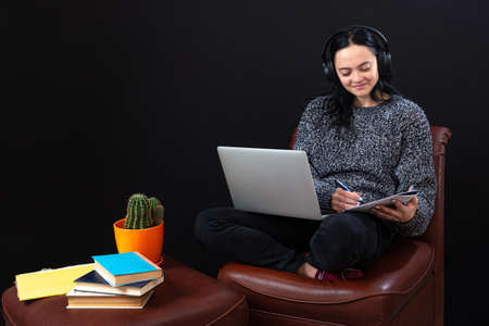 focused young student woman sitting with laptop and headphones, learning remotely online from home