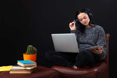 focused young student woman sitting with laptop and headphones, learning remotely online from home