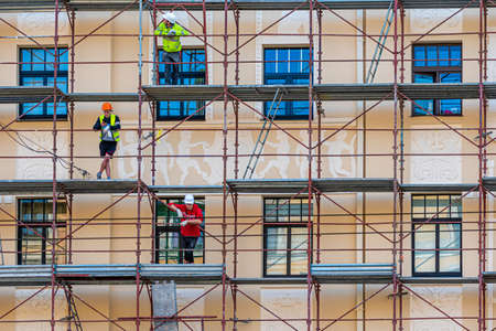 Riga, Latvia - September 30, 2020: construction workers in scaffolding on the building facade for...