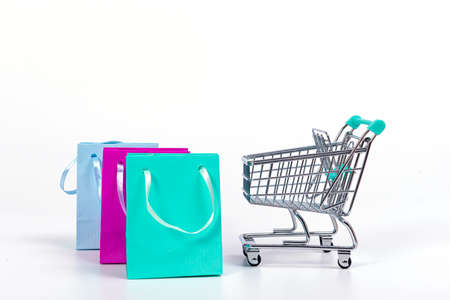 empty mini shopping cart and colourful paper bags isolated on light background, mockup for designの写真素材