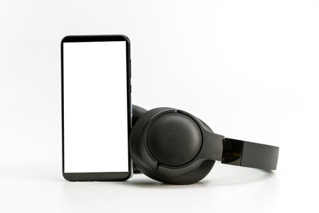 black wireless headphones and smartphone on white background, blank screen mockup, copy spaceの写真素材