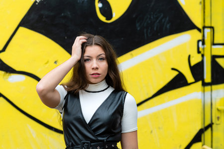 positive young girl portrait on blurred wall sprayed with graffitiの写真素材