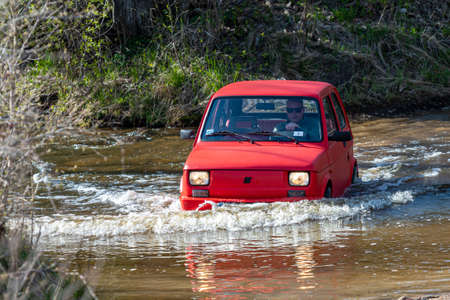 Madona, Latvia - May 01, 2021: red oldtimer car Fiat 126 overcomes water obstacleのeditorial素材