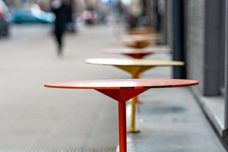 row with empty street cafe tables on defocused city background, pandemic limit conceptの写真素材
