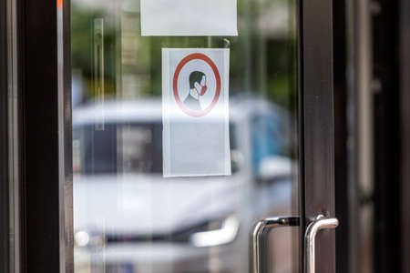 requirement to wear a face mask before entering a building on a glass door at the entrace
