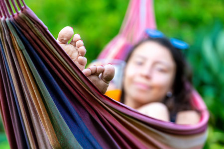 woman is chilling and relaxing in the hammock, selective focus, focus on the feetの写真素材