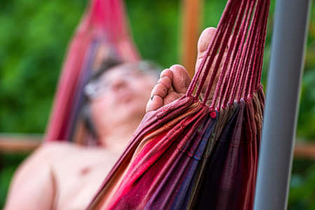 man is chilling and relaxing in the hammock, selective focus, focus on the feetの写真素材