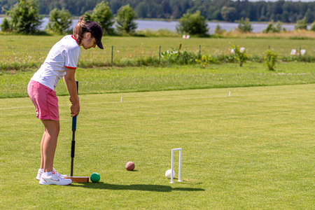 Ikskile, Latvia - July 4, 2021: a young woman playing croquet on the lawn, family activity concept