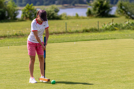 Ikskile, Latvia - July 4, 2021: a young woman playing croquet on the lawn, family activity concept