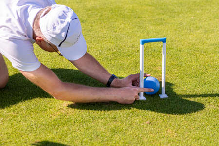 Ikskile, Latvia - July 4, 2021: the man evaluates the situation of the croquet game