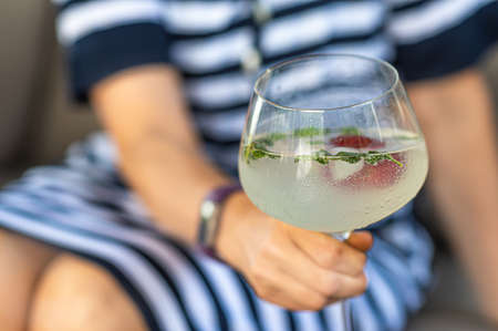 womans hand holding a cocktail glass with blurred background, closeup