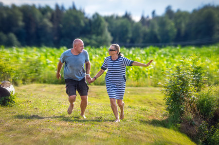 romantic middle-aged couple holding hands running in the garden, the concept of a happy relationshipの写真素材