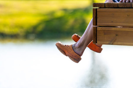 a woman sits on the edge of a footbridge and swings her legs over the lake water
