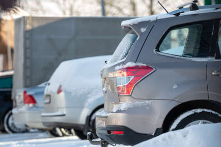 row of different cars parked  in the outdoor parking lot on a snowy winter dayの写真素材