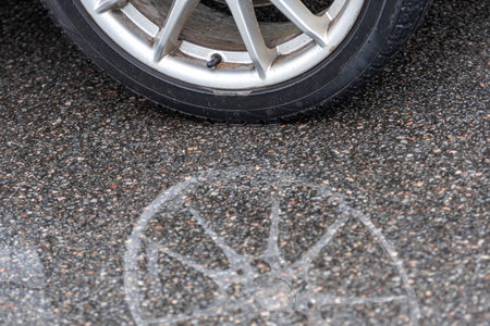 puddle on the pavement with a reflection of the car wheel, close-upの写真素材