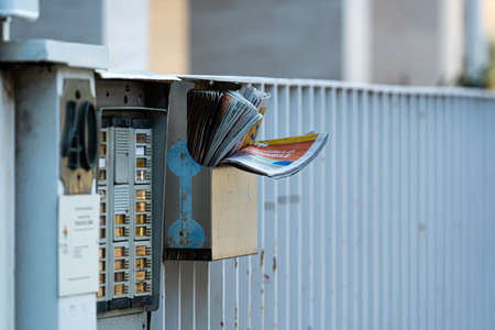 Pisa, Italy - August 9, 2021: mailbox full of advertising and promotional newspapers on the fence...