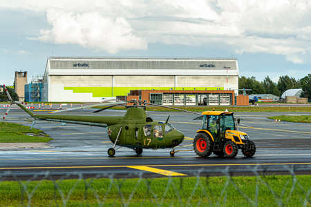 Riga, Latvia - August 19, 2021: the tractor towing old military helicopter (aviation museum exhibit) through the airport territoryのeditorial素材