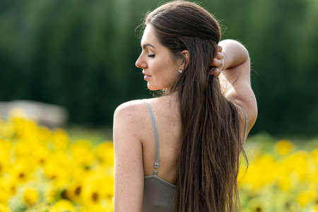 portrait of a beautiful brunette woman in a linen country style dress in a sunflower field