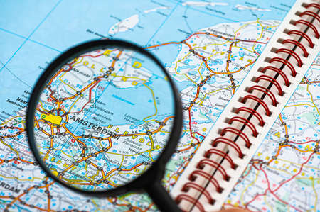 map of Amsterdam in Netherlands through magnifying glass, concept of planning the travel itinerary