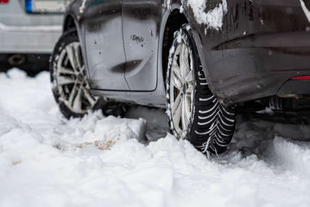 rear view of car with winter tyres in snowy road, close-upの写真素材