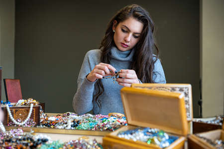 reflection of a woman in mirror choosing and trying different jewelry, soft focus, close-upの写真素材