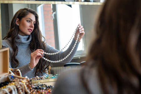reflection of a woman in mirror choosing and trying different jewelry, soft focus, close-upの写真素材