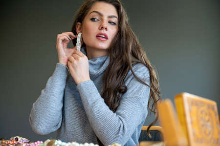reflection of a woman in mirror choosing and trying different jewelry, soft focus, close-upの写真素材