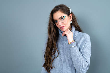 elegant slim woman in glasses and gray sweater isolated on a gray background with copy spaceの写真素材
