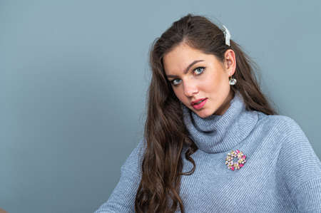 elegant slim woman in a long gray sweater isolated on a gray background with copy spaceの写真素材