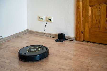 robot vacuum cleaner return to charging at dock in clean room floorの写真素材