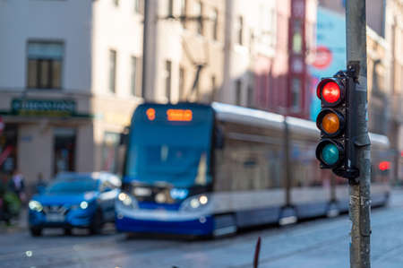 blurred view of city traffic with traffic lights, in the foreground a semaphore with a red lightの写真素材