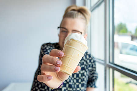 middle aged business woman with glasses offers ice cream, closeup