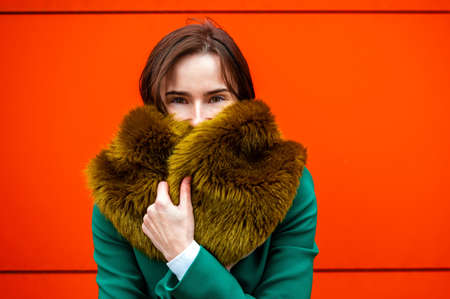 portrait of an elegantly dressed business woman near a orange wall of a modern office building