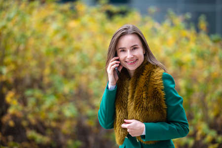 A business woman walking down the autumn park in a financial district talking on the phone