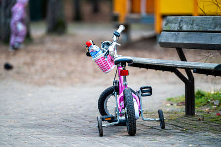 Riga, Latvia, October 30, 2021: pink childrens bike at a bench in the park on a defocused blurred backgroundのeditorial素材