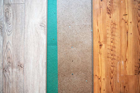 laying a wooden laminate floor in room above a green sound-absorbing base, flooring in the apartment