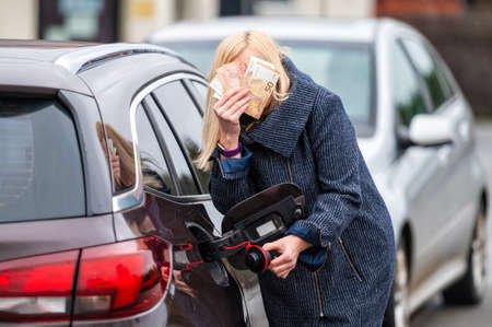 woman with cash near car, the concept of rising fuel prices, expensive fuelの写真素材