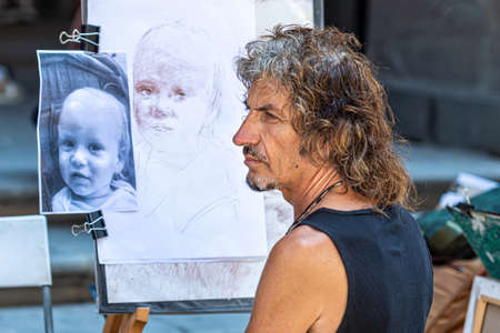 Florence, Italy - August 11, 2021: street artist paints a portrait of a boyのeditorial素材