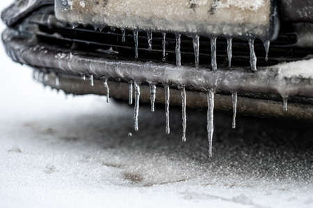A frozen number plate and Ice-covered car bumper with icicles, closeupの写真素材