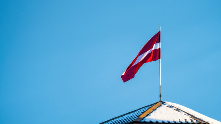Latvian Flag on the flagpole fluttering in the wind against blue clear sky background, copy spaceの写真素材