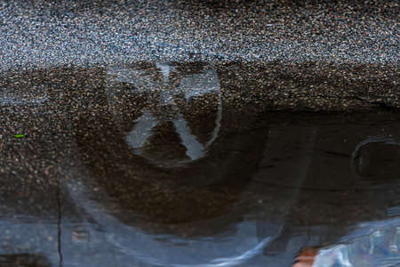 puddle on the pavement with a reflection of the car wheel, close-upの写真素材