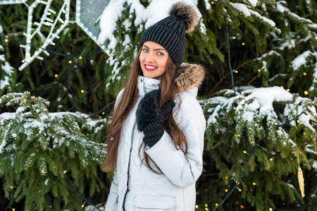 Closeup outdoor portrait of very beautiful young woman over christmas tree lights background