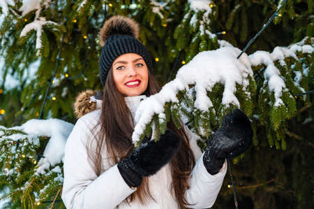 Closeup outdoor portrait of very beautiful young woman over christmas tree lights backgroundの写真素材