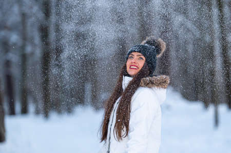 young woman walking in the snowy winter day outdoor, winter forest landscape backgroundの写真素材